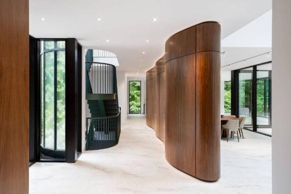 Curved walnut spine wall with the green steel stair beyond